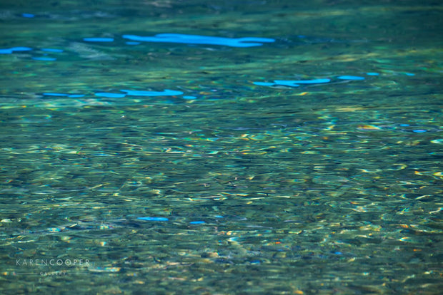rocks on bottom of lake seen through clear blue green water