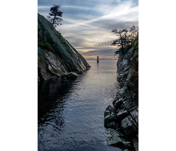 rocky outcrop with buoy on ocean at sunset