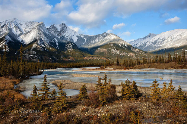 Fine art luxury nature landscape photography  snow covered mountains with river and evergreen and tall trees in the foreground in the winter in British Columbia Canada 