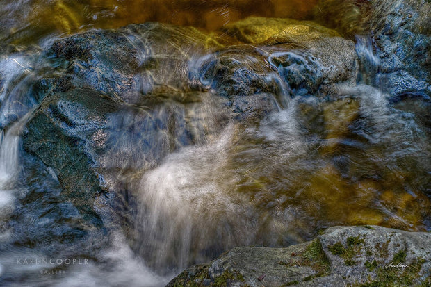 gold water flowing over dark rocks in a creek